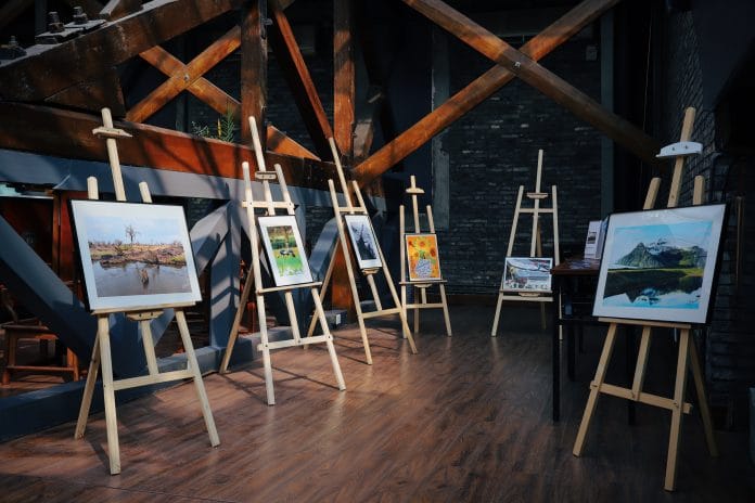 five assorted paintings on easels