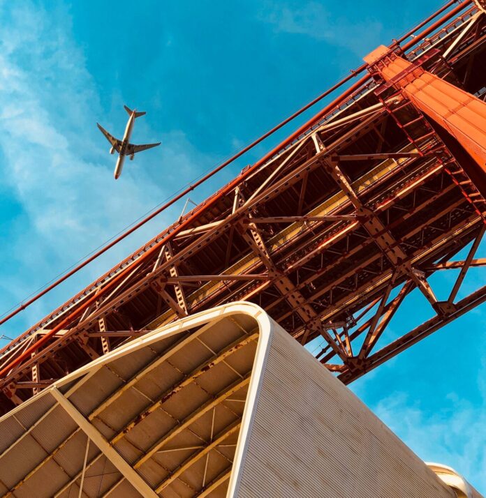 black airplane flying over the bridge during daytime
